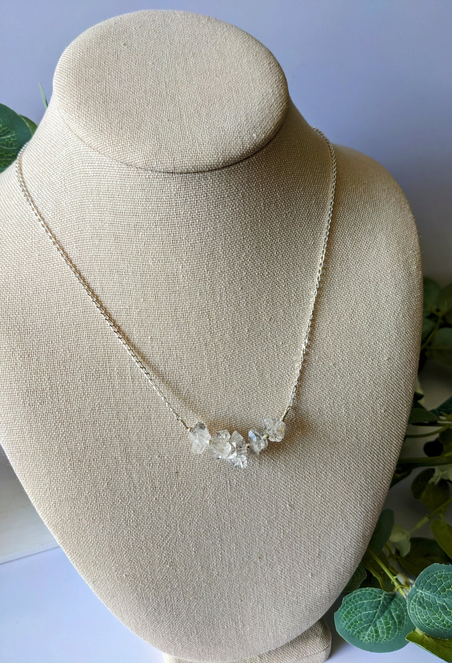 Sterling silver chain with five rough cut HERKIMER DIAMOND stones on a jewelry bust surrounded by greenery